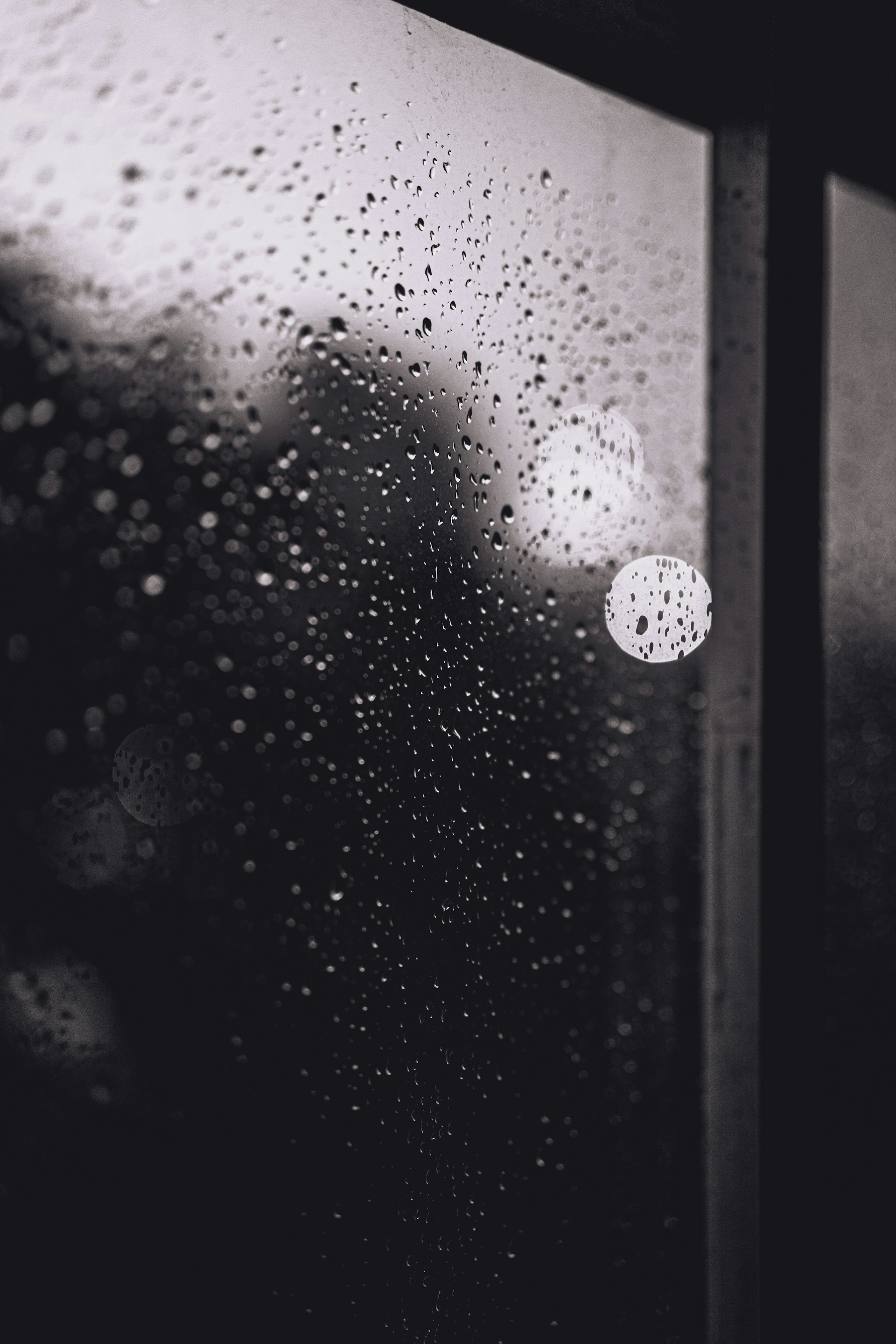 a black and white photo of rain drops on a window
