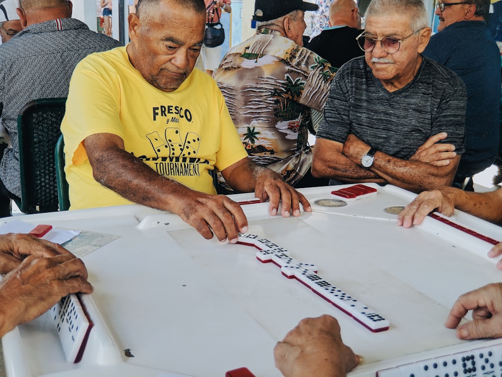 two men sitting while playing dominoes