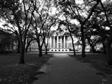 Historic black-and-white photo of the school's founding building surrounded by oak trees.