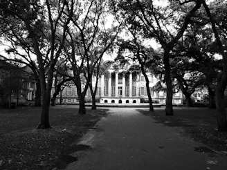 Historic black-and-white photo of the school's founding building surrounded by lush greenery.