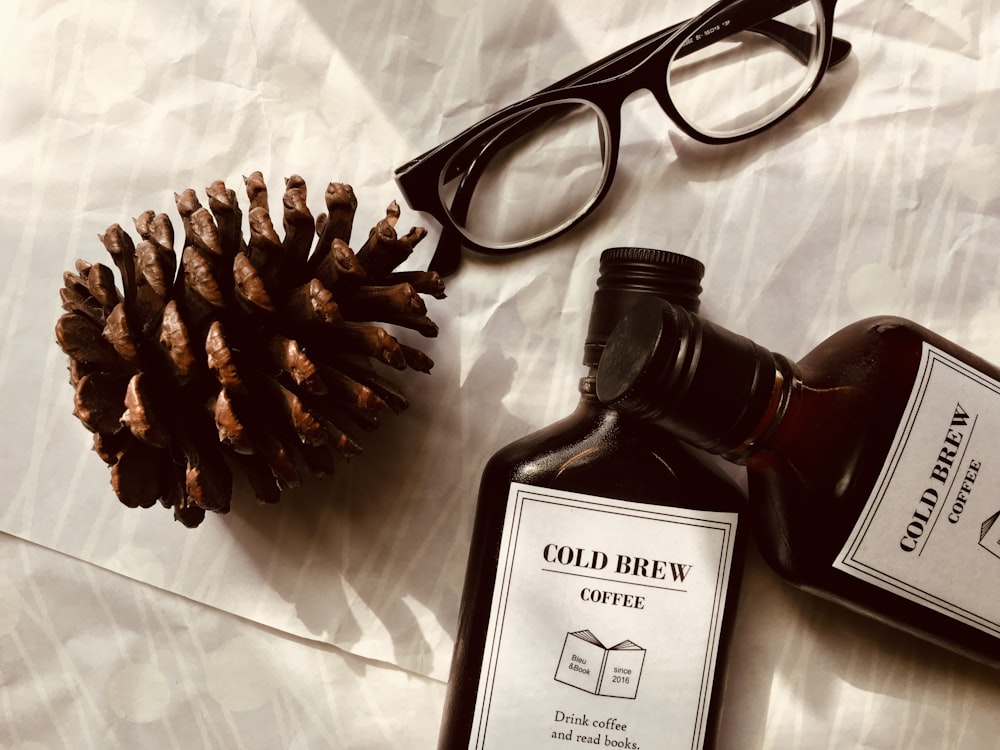 black framed eyeglasses beside two clear-and-white bottles