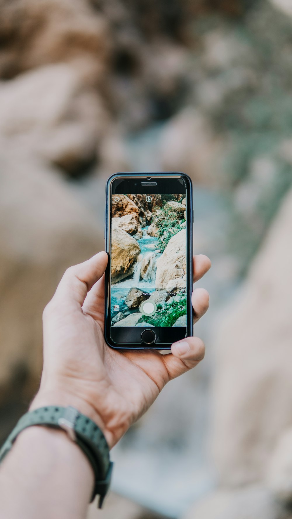 person using iPhone taking picture of river