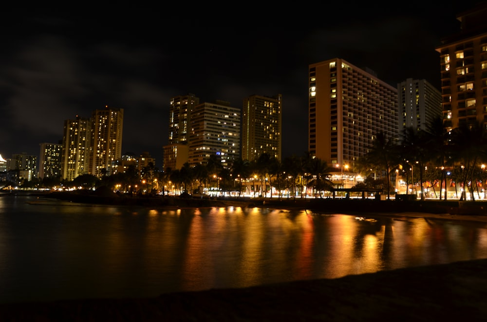 edifícios iluminados perto do corpo de água durante a noite