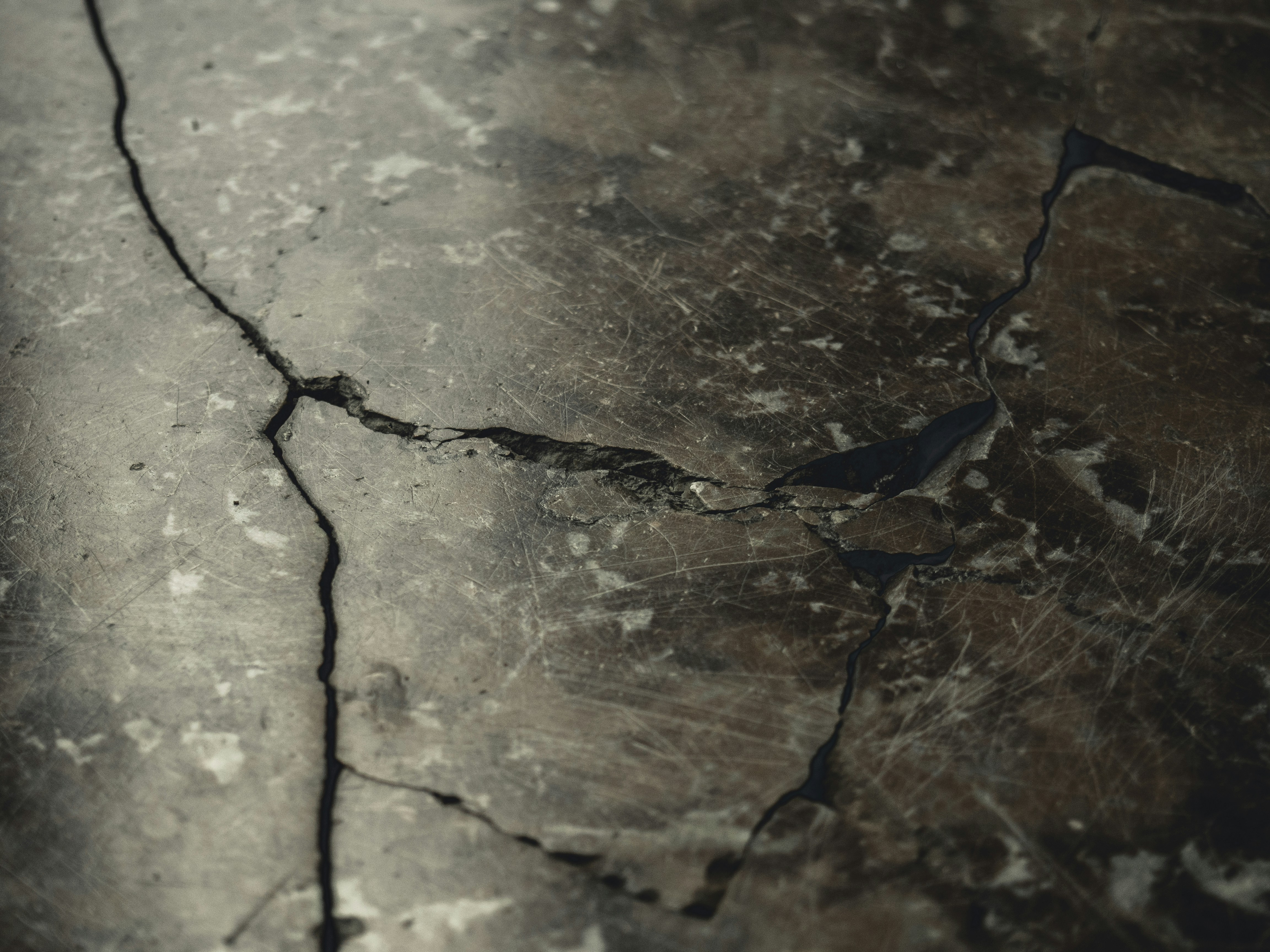 Close-up photo of a cracked concrete wall showing fine structural fissures.