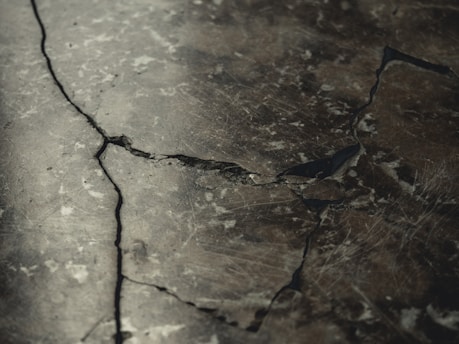 Close-up of cracked concrete beam showing detailed fissures and structural damage.