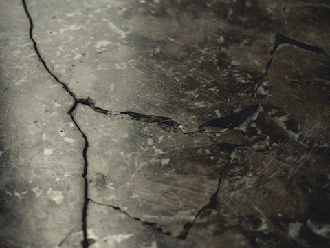Close-up of cracked, weathered concrete driveway before repair.