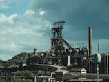 A panoramic view of a bustling steel plant with glowing furnaces and towering smokestacks.