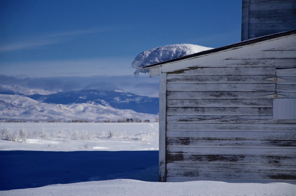 snow formation on top of roof viewing field and mountain covered witrh snow