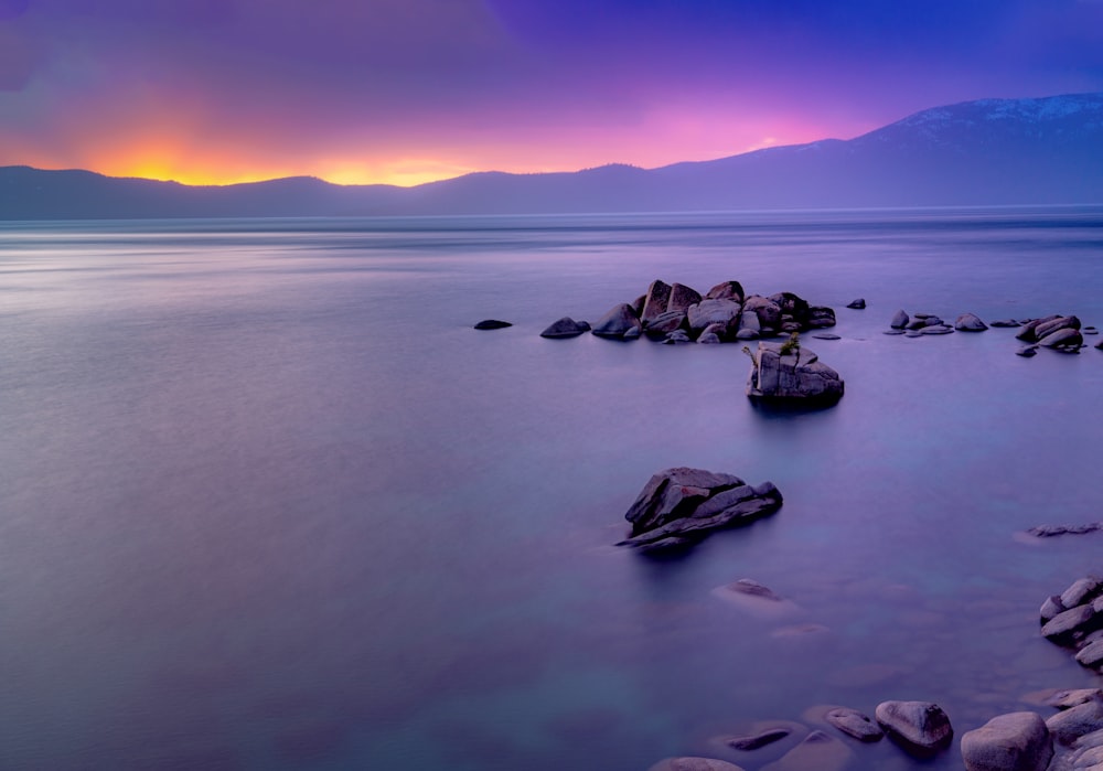 rock formations viewing blue sea and mountain during sunrise