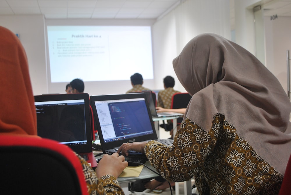 Mujer con hiyab gris usando compiter de computadora portátil