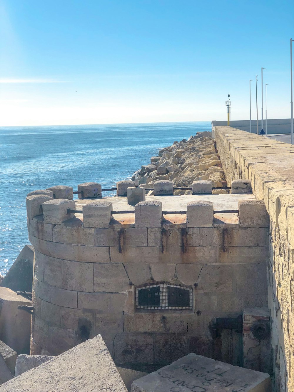 brown pavement viewing blue sea under blue and white skies