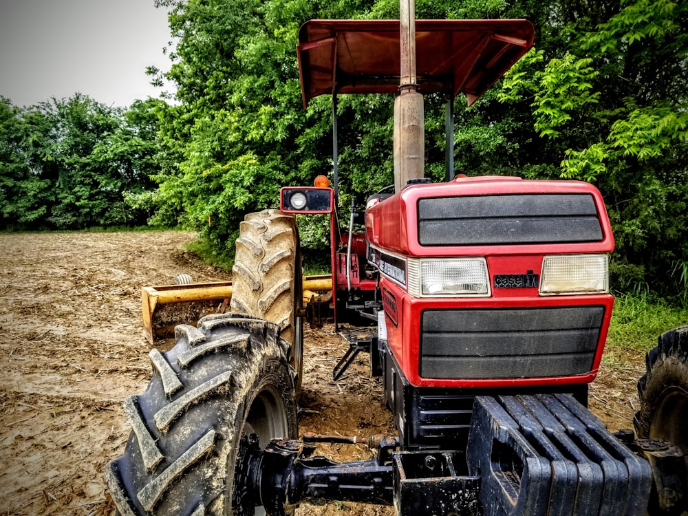 red and black tractor surrounded with tall and green trees