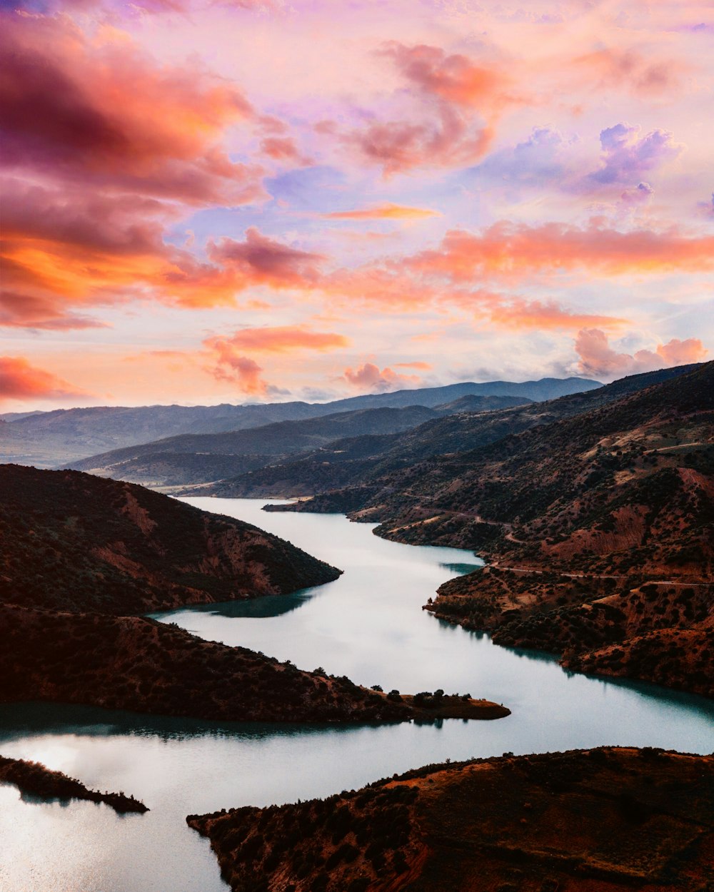 aerial photo of river in between mountain under dramatic clouds during daytime