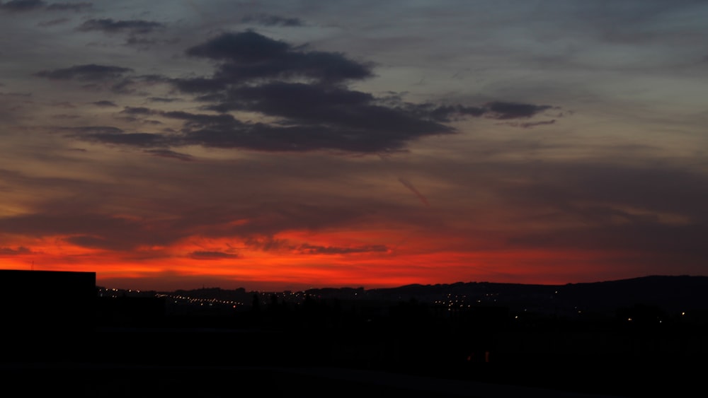 silhouette of mountain under orange and gray skies