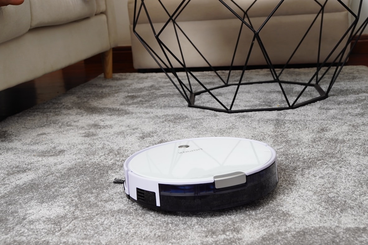 A white robot vacuum on a rug in a modern living room
