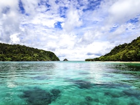 body of water between mountain during daytime