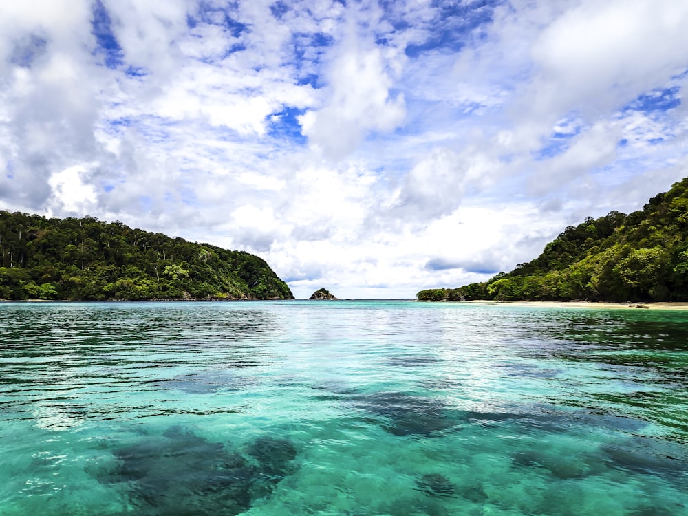 body of water between mountain during daytime