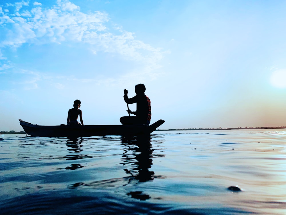 uomo e ragazzo sulla barca sullo specchio d'acqua