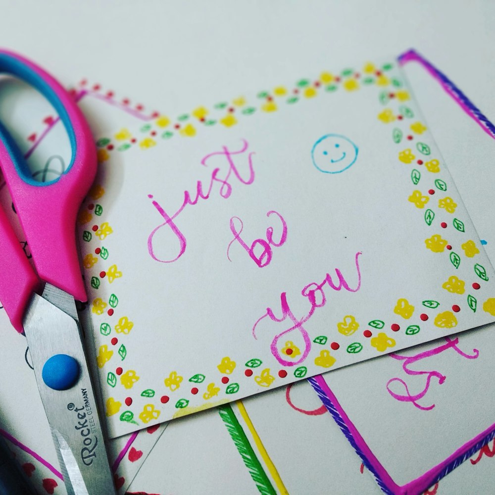 a pair of pink scissors sitting on top of a piece of paper