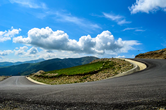 A winding mountain road in Asia with a van navigating the curves under clear blue skies.