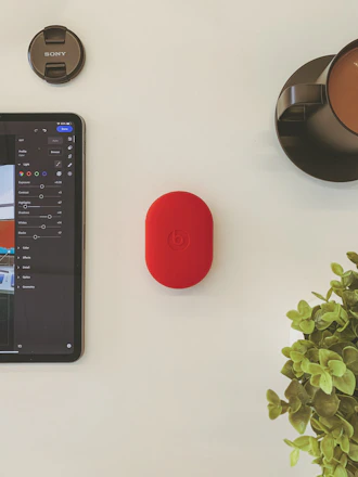 A minimalist workspace with a camera, laptop, and a cup of coffee on a wooden table.