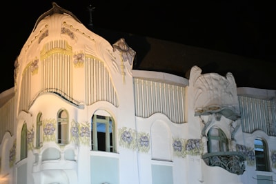 An architectural feature of a building characterized by ornate detailing and decorative elements. The facade includes floral motifs and elegant arched windows, with styling that suggests an Art Nouveau or similar design aesthetic.