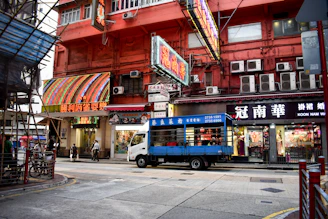 A skilled technician installing a vibrant storefront sign on a busy commercial street.