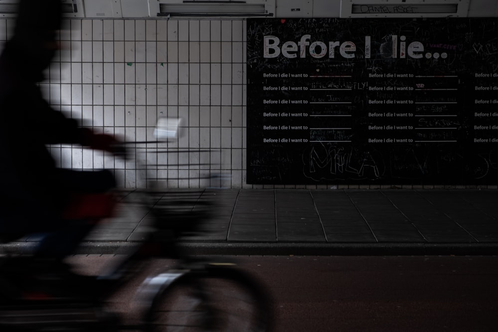 person riding bicycle beside white wall