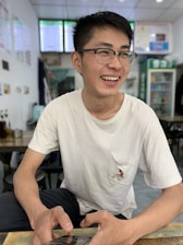 A happy customer trying on stylish prescription glasses indoors with a bright, cozy background.