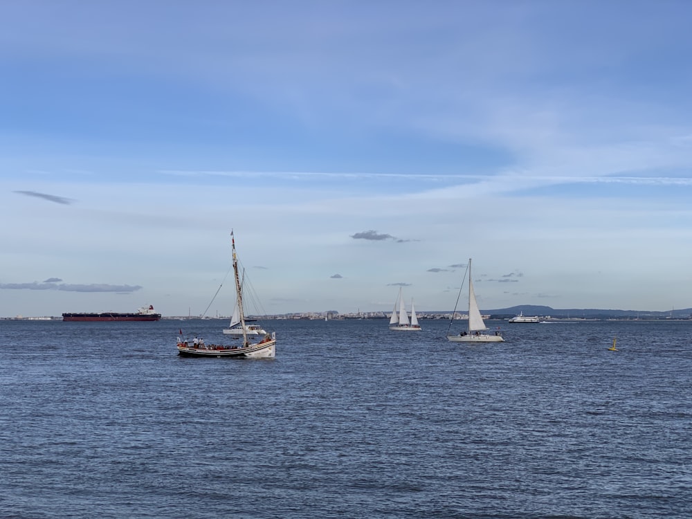 three sailboats on body of water