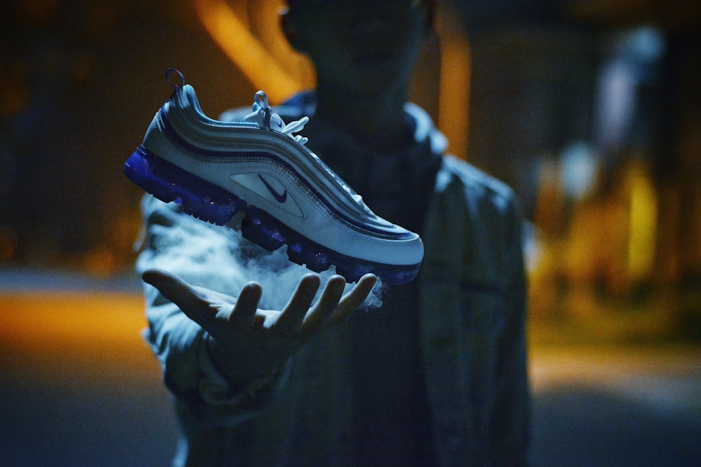 man with unpaired white and blue Nike sneaker in hand