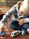 boy sitting on carpet playing car toys