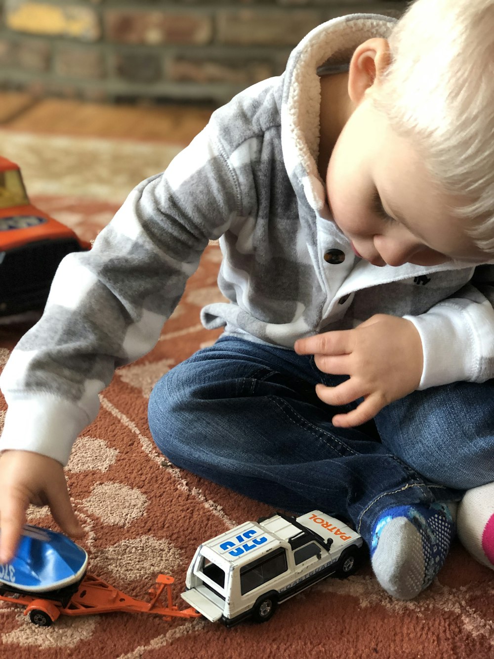 boy sitting on carpet playing car toys