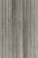 Vertical wooden planks with a weathered appearance, featuring natural textures and patterns formed by grain and knots.