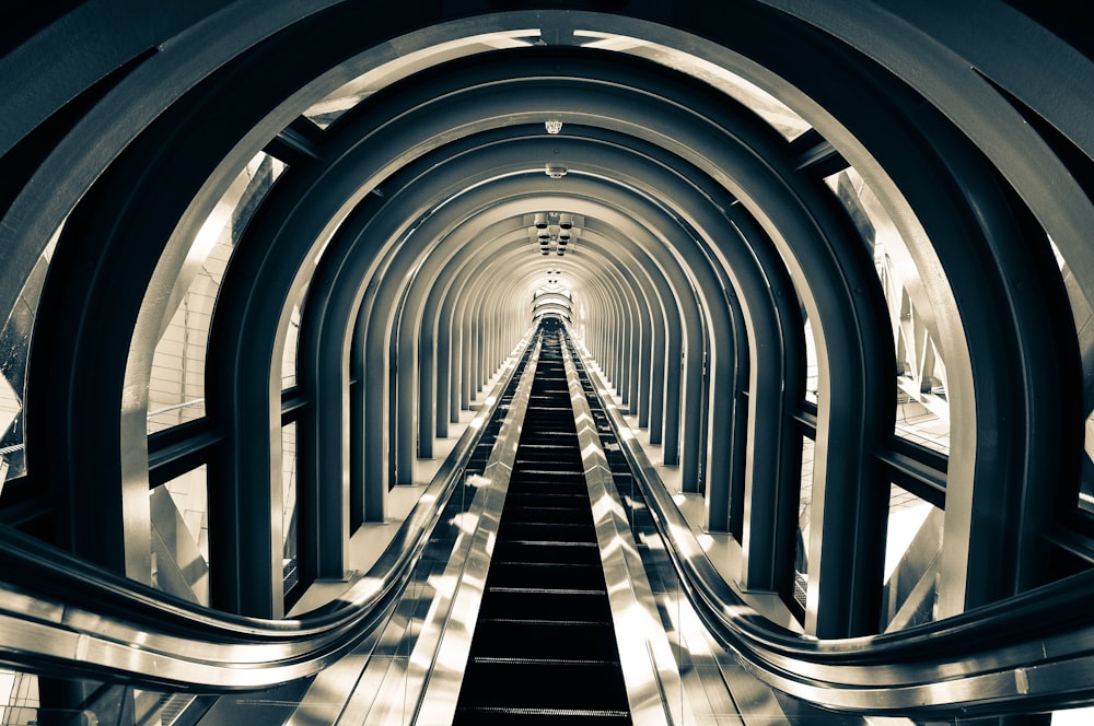 grayscale photo of escalator with no people inside building