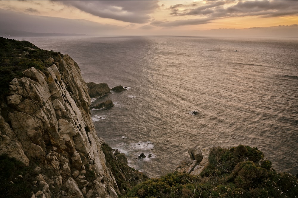 beach cliff viewing calm sea under gray skies