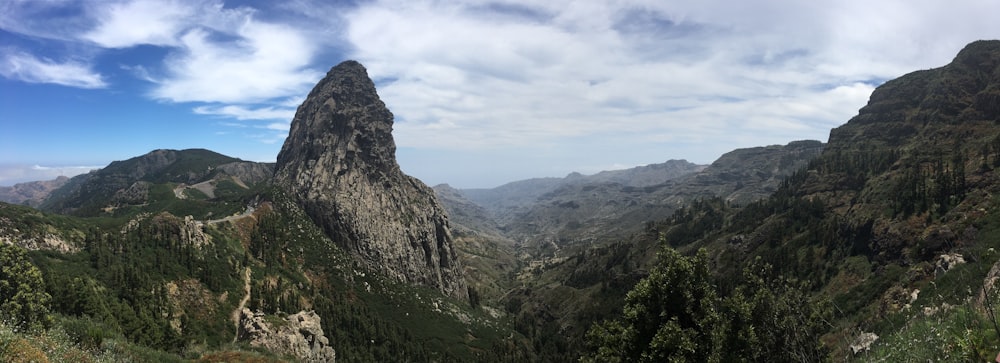 mountain and filed view under blue and white skies