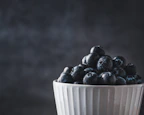 Close-up of a vibrant, hand-glazed ceramic bowl filled with fresh fruit.