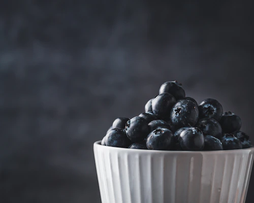 Close-up of a colorful stoneware bowl with a glossy glaze, filled with fresh fruit, highlighting its cozy, handmade charm.