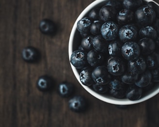 A vibrant display of fresh wild blueberries in a rustic wooden bowl.