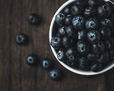 A vibrant display of fresh wild blueberries in a rustic wooden bowl.