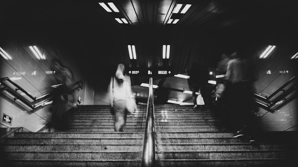 time-lapse and grayscale photo of people walking on staircase