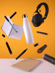 black cordless headphones beside sport bottle and notebook