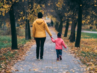 person holding child walking on pathway