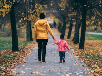 person holding child walking on pathway