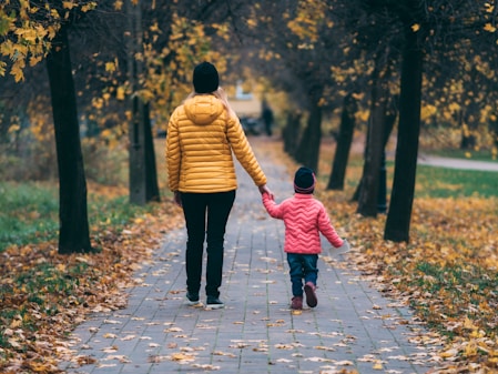 person holding child walking on pathway
