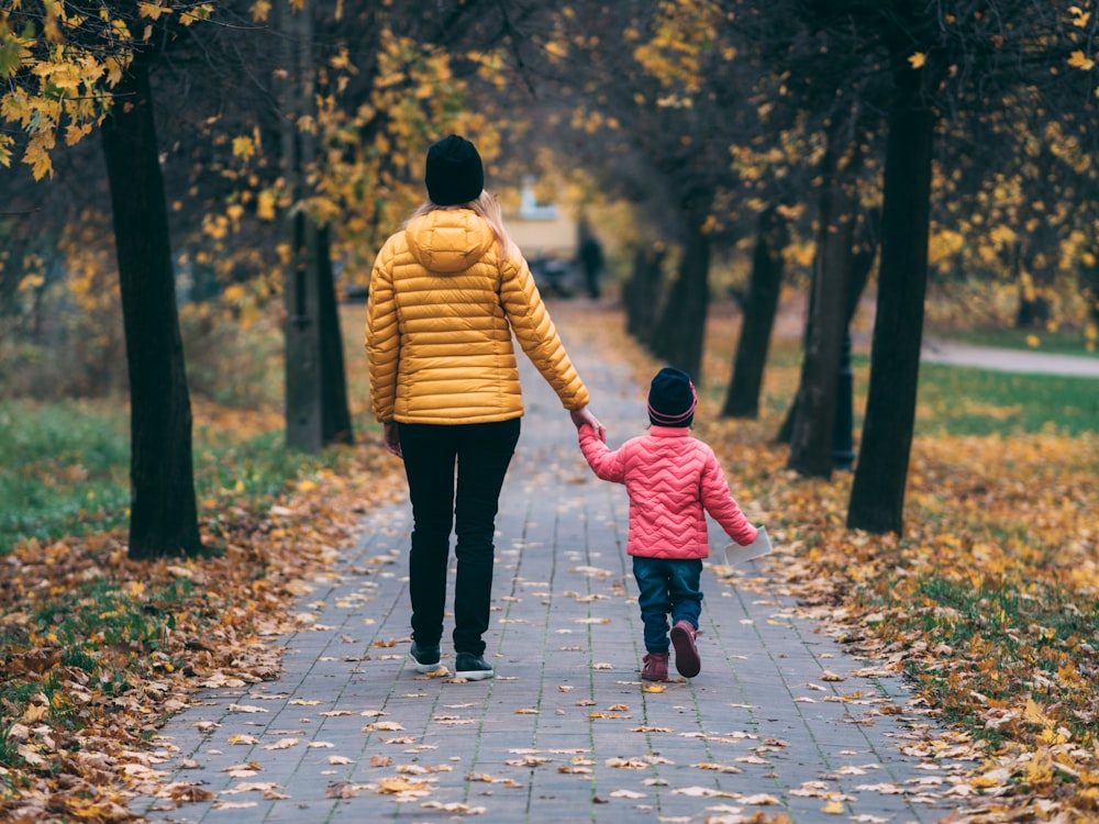 personne tenant un enfant marchant sur le sentier