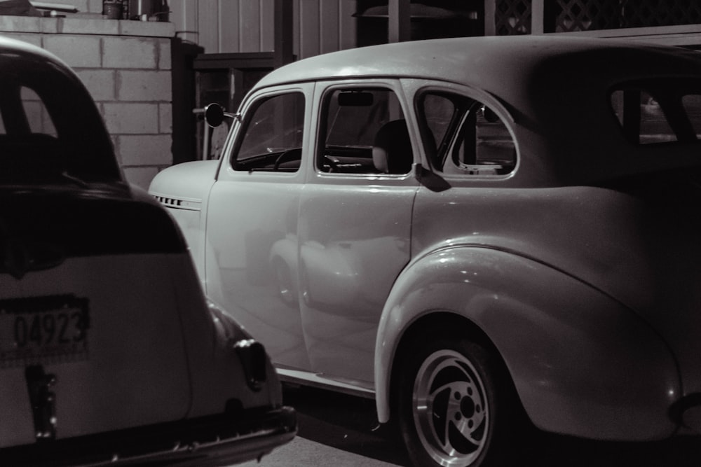 two parked cars near white wall