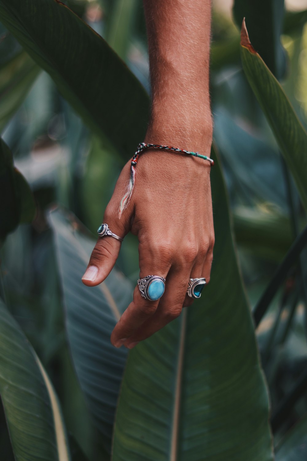 person wearing three silver-colored blue gemstone rings