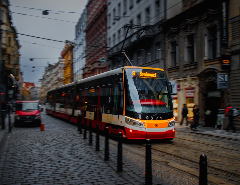 white and red train bus between buildings